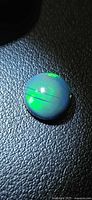 Top view of round cabochon Ethiopian black opal showing green play-of-color