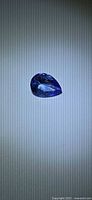 Pear-shaped tanzanite on neutral background full view