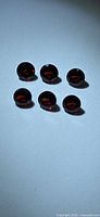 Six faceted garnets face-up showing cherry red hue