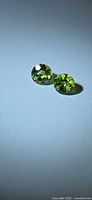 Two round green peridot gemstones on neutral background