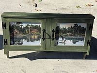 Full view of green accent cabinet with two scenic front panels