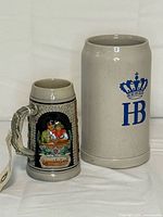 Both stoneware beer steins side by side for scale and design comparison