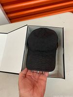 Black Gucci GG monogram baseball cap displayed inside open Gucci box