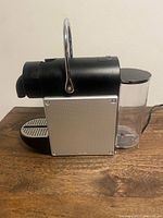Side view of Nespresso Pixie showing aluminum panel, handle, water tank
