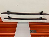 Top view of both crossbars laid parallel showing full length and mounts