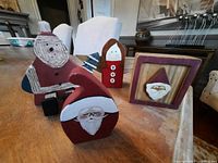 All four hand-painted wooden Christmas decorations on table