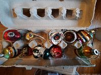 All ten glass ornaments arranged in cardboard egg carton