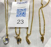 All four gold-tone necklaces with pendants displayed