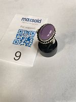 Front view of sterling silver ring displaying oval purple amethyst cabochon and decorative rope bezel