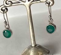 Full view of both sterling silver earrings hanging to show green onyx stones