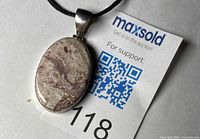 Front view of orca agate pendant on black cord showing stone pattern and silver bezel