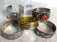 Group of five cuff bracelets showing styles and finishes