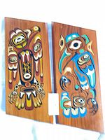 Front view of both cedar plaques showing carved and painted designs