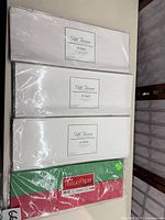 stacked tissue paper packs showing three white 35-sheet packs and one red/green pack