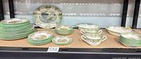 Overall lot showing stacked dinner plates, smaller plate stacks, twin-handled cups, and two oval serving platters