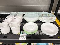 Assorted Corelle mugs, creamers, bowls and plate stacks on shelf