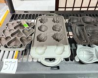 Three John Wright cast iron baking molds on rack; heart/shell pan, fruit/shell pan, hot-air-balloon pan visible
