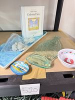 All items grouped on shelf: glass fish hanger, blue ceramic tray, note cards box, ornament, small lobster dish