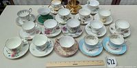 All 18 teacup and saucer sets arranged with ruler for scale