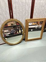 Round and rectangular gilt mirrors leaning against wall