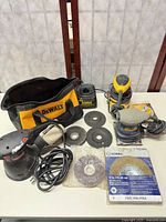 Overview of three sanders, charger, discs, bag