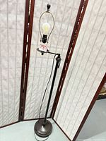 Full view of metal floor lamp showing base, pole, harp, bulb, and missing shade
