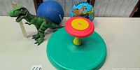 Overall lot view with all four items: Sit 'n Spin, Scooby-Doo ball, blue playground ball, T-Rex figure