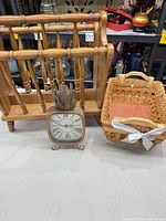 Front view of wooden magazine rack, metal pineapple clock, and woven basket