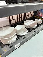 Stacked dinner plates, salad plates, bowls and ramekins on shelf