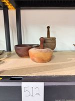 Three wooden vessels and pestles on shelf