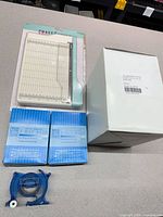 Overall lot showing paper trimmer, two ZIG glue pen boxes, Scotch tape dispenser, white carton