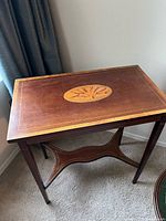 Full view of mahogany side table showing top with oval fan inlay, string inlay border, tapered legs and stretcher
