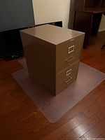 Front and side view of tan two-drawer metal filing cabinet showing overall condition