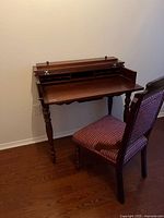 Desk open showing slide-out writing surface and interior cubbyholes with chair in front
