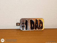 Front view of metal “#1 DAD” tag pendant showing design and bail