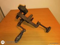 Side view of cast iron clamp-on hand-crank grinder showing stone and handle