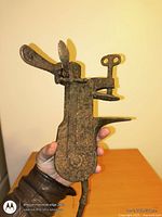 Full view of ornate cast iron grinding tool held in hand