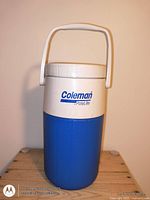 Front view of blue and white Coleman PolyLite water jug with handle