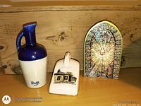 Front view of Delft jug, rectangular plaque with building illustration, and arched stained-glass style plaque