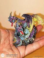 Double-headed resin dragon figurine in hand for scale