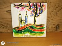 Front of tile under bright light showing full painted scene and signature