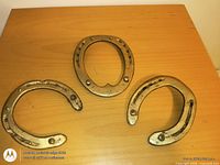Three gold painted iron horseshoes on wooden surface