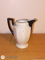 Front view of lusterware pitcher with black handle and spout