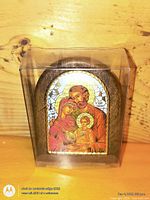 Front view of arched metal Holy Family icon inside clear box