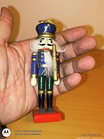 Front view of wooden nutcracker ornament held in hand for scale