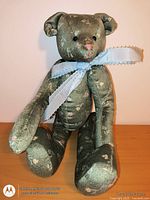 Front view of green floral teddy bear seated on table
