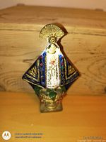 Front view of carved religious figurine showing cloak, halo, base