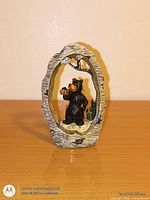 Front view of resin black bear figurine inside faux tree trunk frame