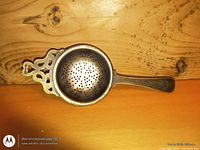 Top view of silver-plated tea strainer showing perforated bowl and handle detail