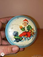 Top view of blue round tin showing child on sled and dog illustration, wear visible